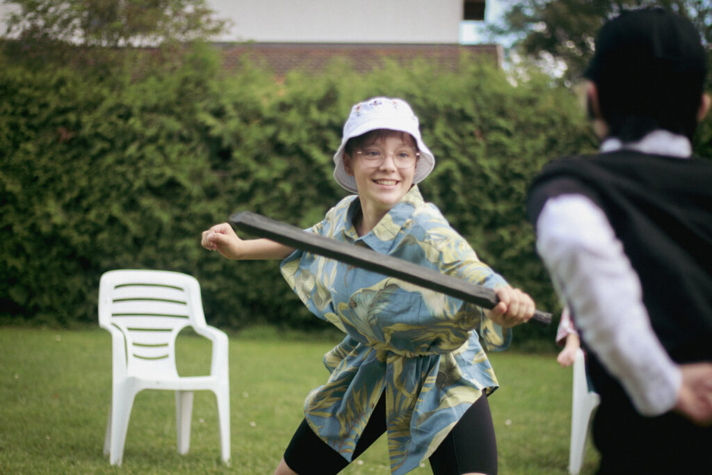 Une adolescente en colonie de vacances inclusives participe à une joute à l'épée en mousse
