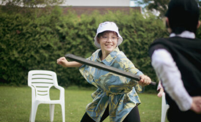 Une adolescente en colonie de vacances inclusives participe à une joute à l'épée en mousse