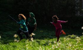 Groupe de jeunes participant à une colonie de vacances inclusive, assis en cercle dans un espace naturel verdoyant