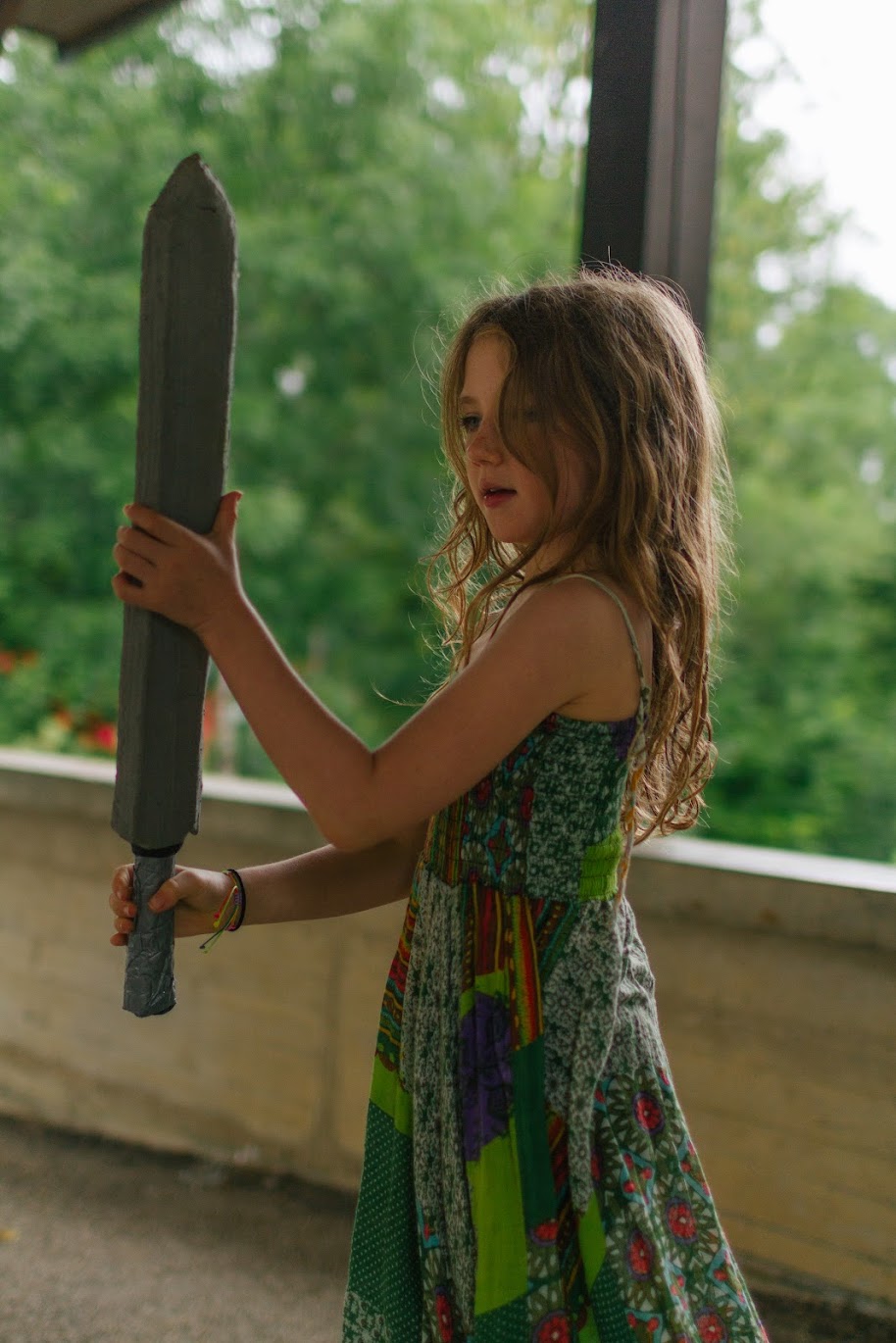 Une enfant pose avec une épée lors d'une colo de l'été 2023