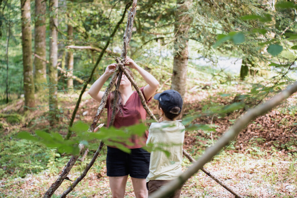 Anim et enfant fabriquant une cabane en colonie de vacances