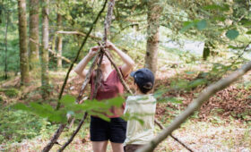 Anim et enfant fabriquant une cabane en colonie de vacances