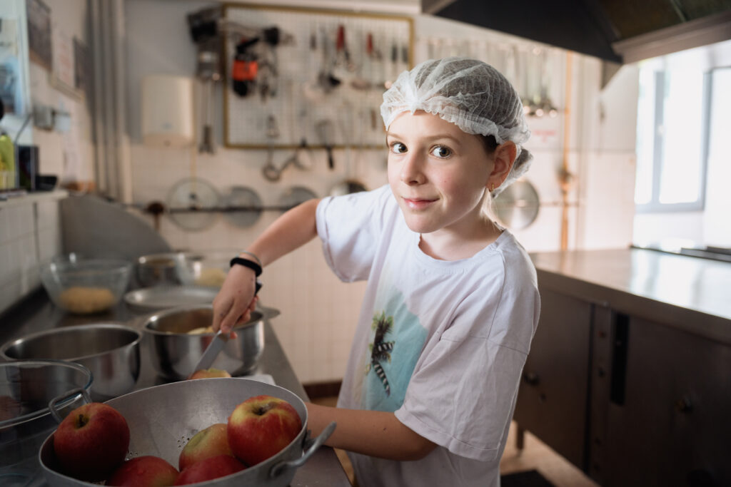 Ado cuisinant des aliments lors d'une colonie de vacances inclusive et écoresponsable organisée par Toustes en Colo
