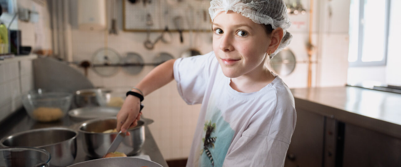 Ado cuisinant des aliments lors d'une colonie de vacances inclusive et écoresponsable organisée par Toustes en Colo