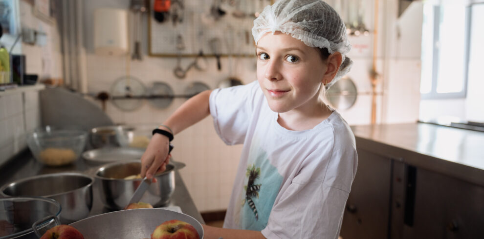 Ado cuisinant des aliments lors d'une colonie de vacances inclusive et écoresponsable organisée par Toustes en Colo
