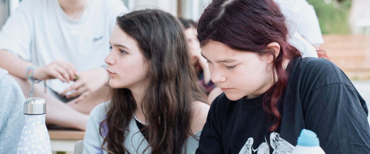 Enfants en cercle lors d'une colonie de vacances écoresponsable, prenant une décision collective sans adulte au centre