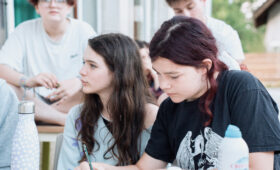 Enfants en cercle lors d'une colonie de vacances écoresponsable, prenant une décision collective sans adulte au centre