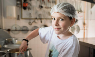 Ado cuisinant des aliments lors d'une colonie de vacances inclusive et écoresponsable organisée par Toustes en Colo