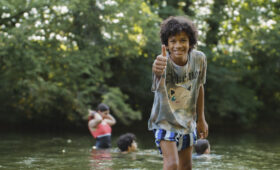 Groupe d'enfants et d'animateurs souriants en colonie de vacances inclusive dans le Jura avec Toustes en Colo